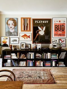 there are many pictures on the wall in this living room with bookshelves and shelves