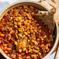 a bowl filled with beans and bread on top of a table