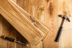 tools are laying on the floor next to some wood planks, including a hammer and screwdriver