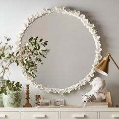 a round mirror sitting on top of a white dresser