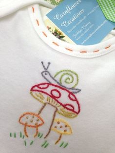 a close up of a baby's bib with an embroidered mushroom on it