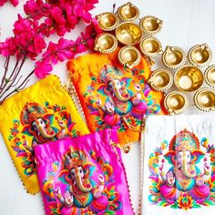 four colorfully decorated napkins sitting on top of a table next to gold dishes and flowers