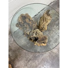 a glass table topped with driftwood pieces on top of cement flooring next to a white brick wall