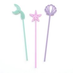 three little mermaid wands are shown on a white surface, one has a starfish and the other has a fish tail