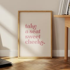 a framed poster with the words take a seat, sweet cheeks on it next to a computer keyboard