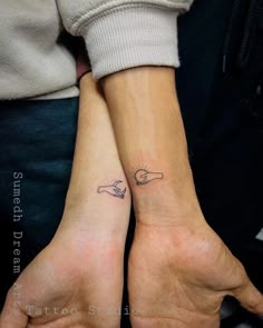 two people with matching wrist tattoos holding hands