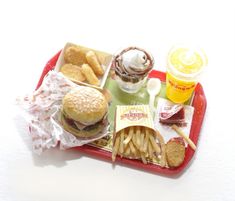 a tray that has some food on it and fries in front of the tray with drinks