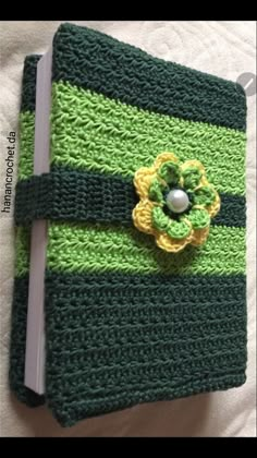 a green and yellow crocheted book with a flower on it's cover