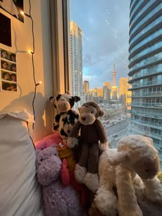 several stuffed animals are sitting on a window sill in front of a cityscape