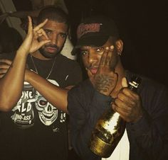 two men are posing for the camera with one holding a bottle in front of his face