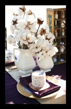 a white pitcher filled with cotton sitting on top of a table next to a cup and saucer