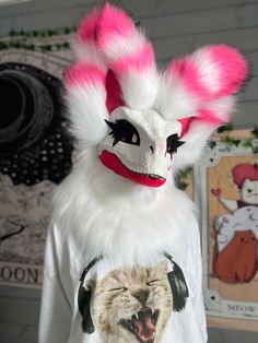 a white and pink mask with headphones on it's face, sitting next to a t - shirt