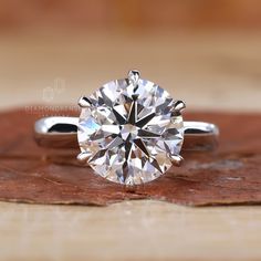 a diamond ring sitting on top of a piece of wood with the center stone missing