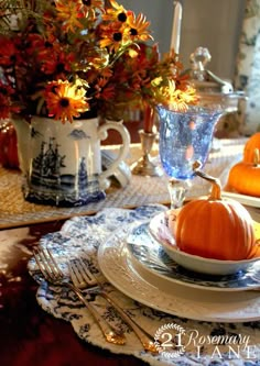 a table set for thanksgiving with pumpkins and flowers