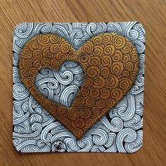 a paper cut out of a heart on top of a wooden table with swirls