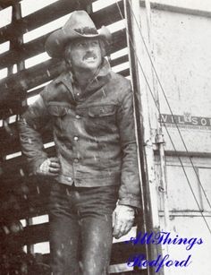 an old black and white photo of a man standing next to a truck