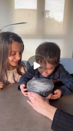 two children sitting at a table with a cake in front of them