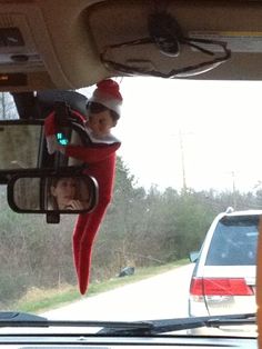 an elf is hanging out the car window in front of another person who is driving