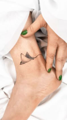 a woman's foot with a small tattoo on her left ankle and green nail polish