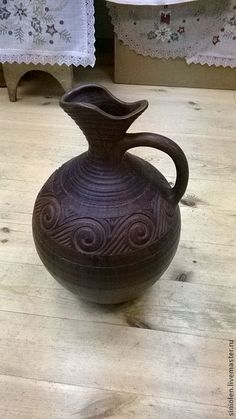 a brown vase sitting on top of a wooden table next to two white doily curtains