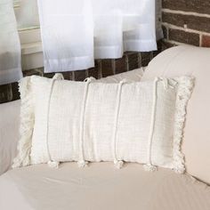 a white pillow sitting on top of a bed next to a brick wall and window