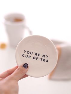 a person holding up a white plate with the words you're my cup of tea on it