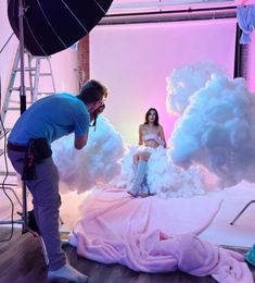 a man and woman standing in front of a white cloud backdrop while another person takes a photo