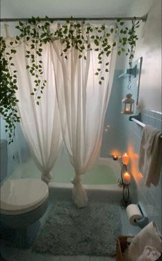 a bathroom with a toilet, shower curtain and candles in the bathtub next to it