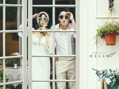 a man and woman standing in front of a window