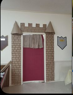 an empty room with a red door and brick castle like structure on the wall above it