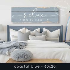 a bed with pillows and blankets next to a wooden sign that says relax you're on beach time