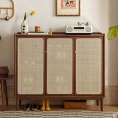 a brown cabinet sitting in the middle of a living room next to a chair and rug