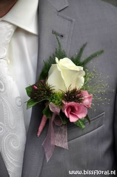 a man in a gray suit with a pink and white boutonniere