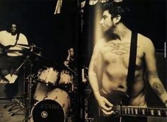 an image of a man with no shirt on playing the guitar and drummer behind him