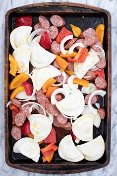 a tray filled with sausage, peppers and onions