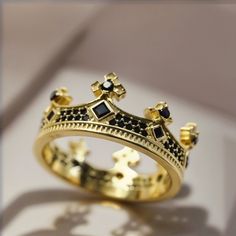 a gold crown ring with black stones on it