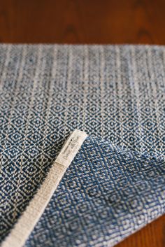 a close up of a blue and white cloth on a wooden table with a tag