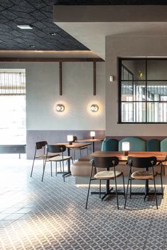 an empty restaurant with tables and chairs in the center, lights on above them are lit by two lamps