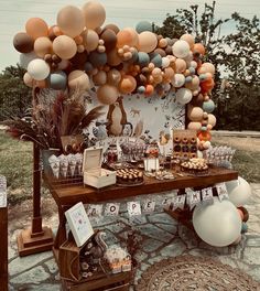 a table topped with lots of balloons next to a wall filled with pictures and desserts