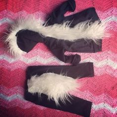 two pieces of black and white fur on top of a pink blanket next to a pair of leggings