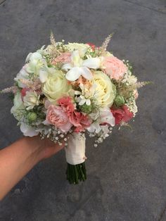 a bridal bouquet being held by someone's hand on the ground in front of them