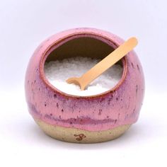 a pink and brown ceramic bowl with a wooden spoon in the center on a white background