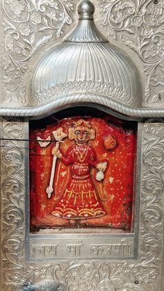 an intricately decorated metal box with a statue in it