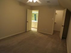 an empty room with a ceiling fan in the corner and two closets on either side