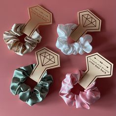 four scrunffle hair ties in different colors on a pink background, one with a diamond and the other with a ring