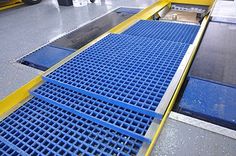 a conveyor belt with blue grates on the bottom and yellow trim around it