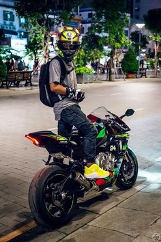 a man sitting on top of a motorcycle in the middle of a street at night