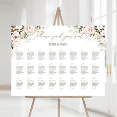 a wedding seating chart with pink flowers and greenery on the top, in front of a window