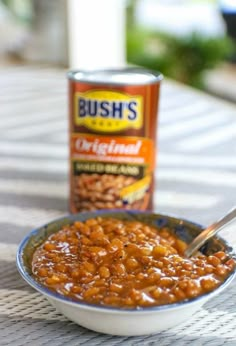 a bowl of baked beans next to a can of bush's