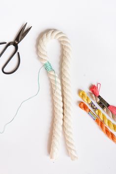 the scissors are next to several different colored yarns and thread on a white surface